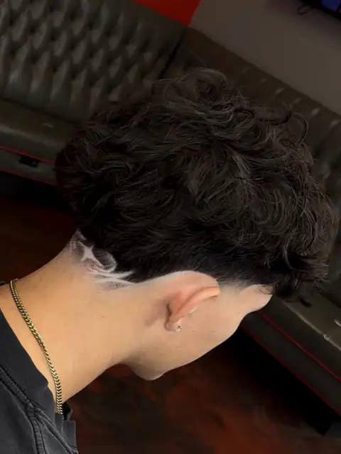 Textured top with a taper and a freestyle design behind the ear, cut by Raekwon