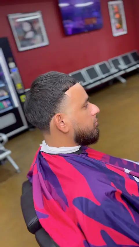 Slicked top with a taper and a lined beard, cut by Jr