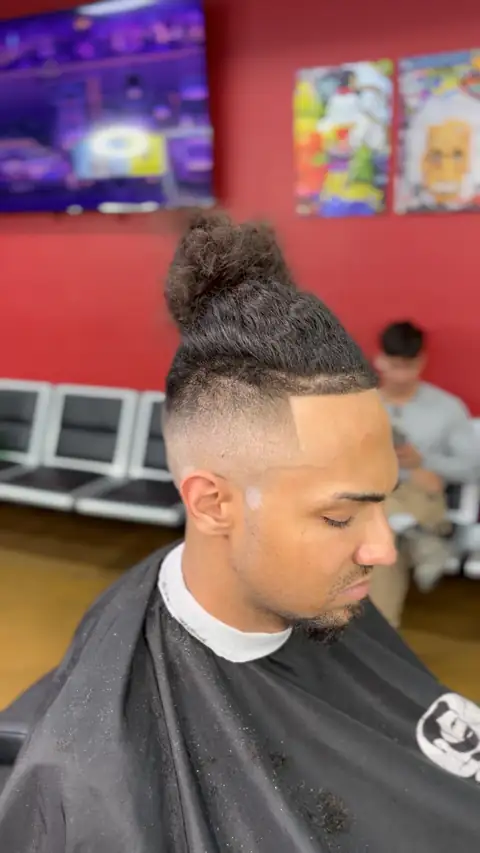Man bun with a high skin fade and a sharp line up, cut by Jr