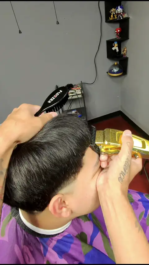 A barber blending a taper with gold clippers at the Peoria Ave shop